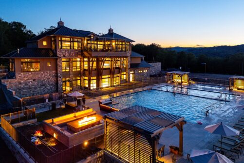 Serenite Clubhouse Serenite Private Members Club Illuminated luxury clubhouse next to an outdoor swimming pool at twilight