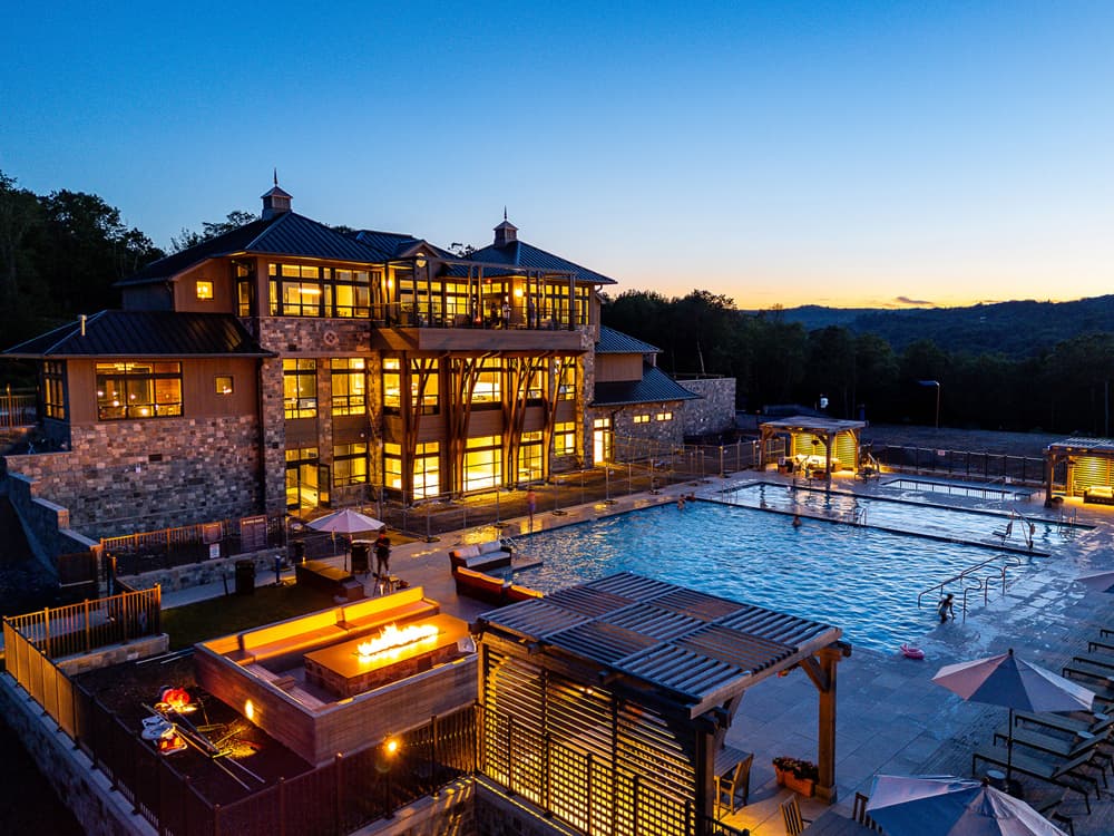 Serenite Private Members Club Illuminated luxury clubhouse next to an outdoor swimming pool at twilight Serenite Private Members Club Illuminated luxury clubhouse next to an outdoor swimming pool at twilight